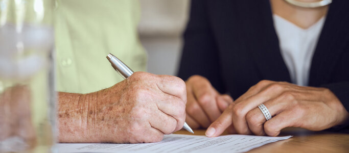 Senior woman signing estate planning documents with a lawyer